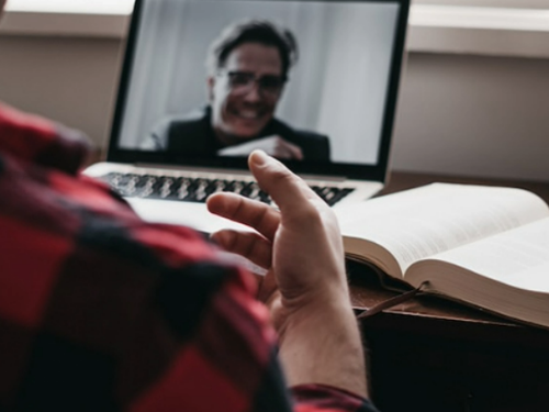 A person sat at a laptop whilst on video call with another person.