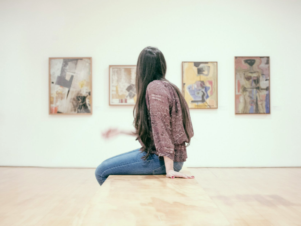 woman sat on bench in middle of art gallery